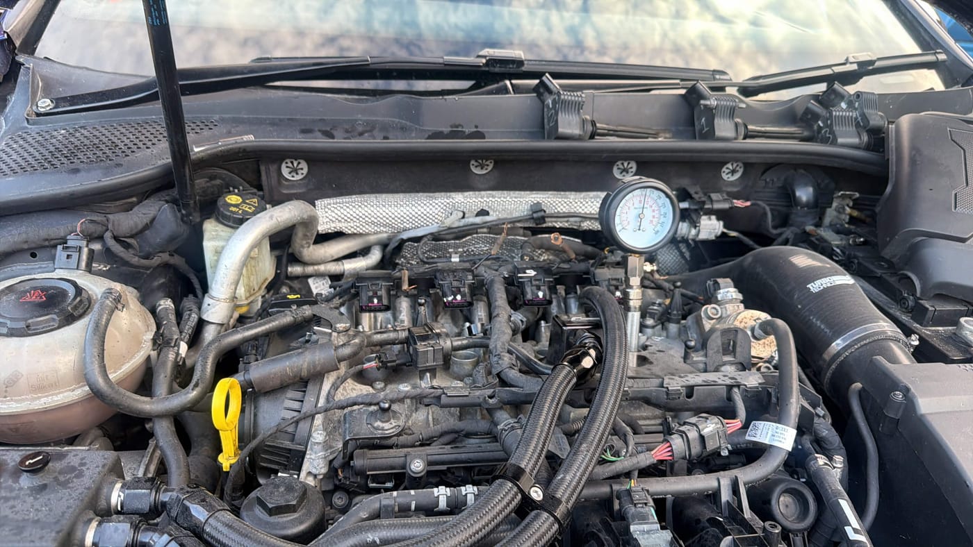 Compression tester fitted in an engine bay